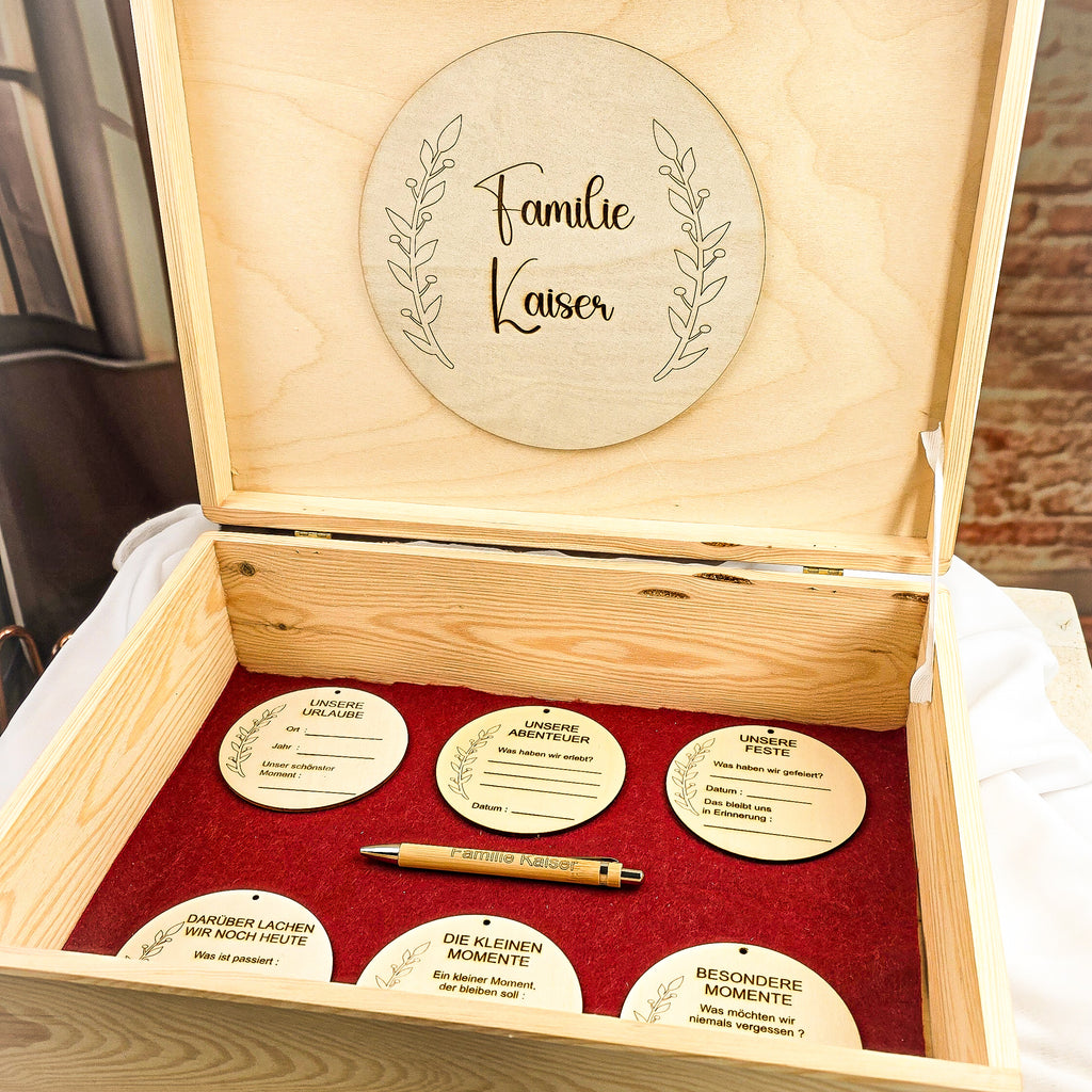Personalisierte Erinnerungsbox aus Holz geöffnet – 6 gravierte Holzanhänger auf roter Filzeinlage mit Bambus-Kugelschreiber und individueller Namensgravur im Deckel